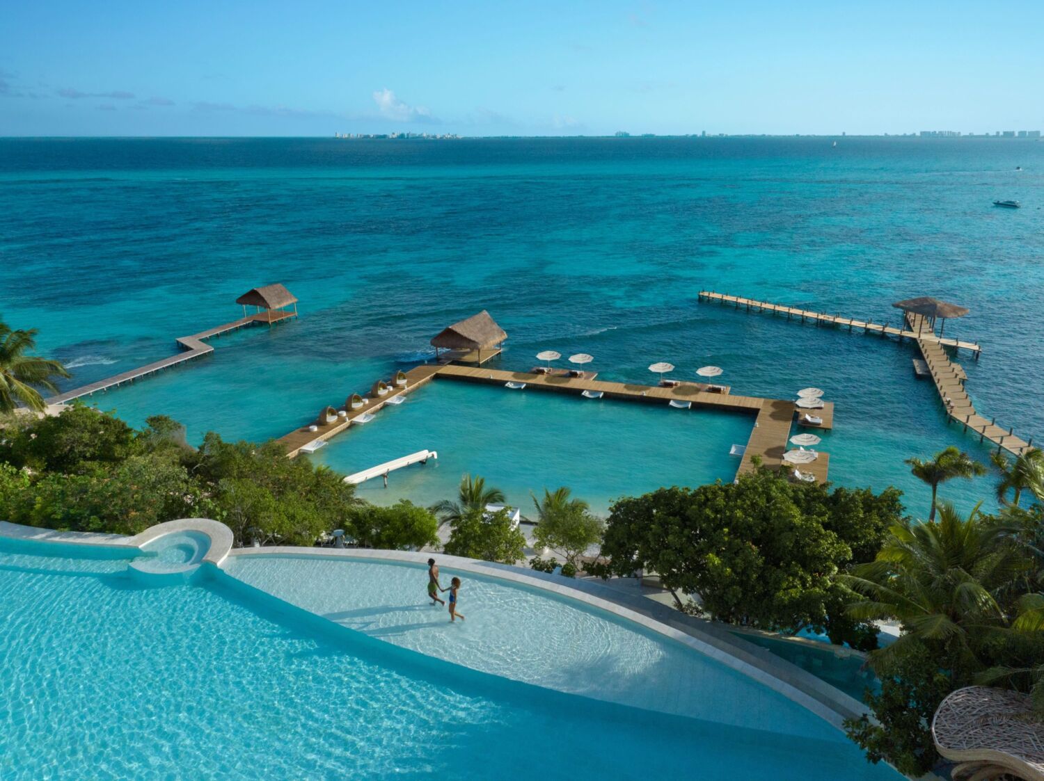 Aerial view of the infinity pool, over-water decks and palapa piers at Impression Isla Mujeres