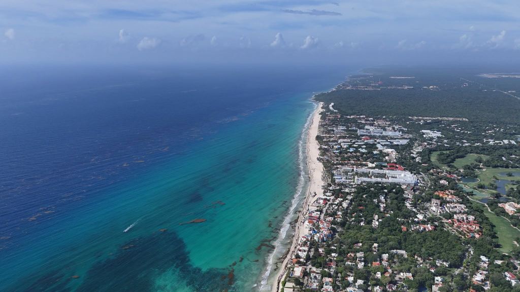 Aerial view of Playacar Fase 2: a long white beach backed by resorts, with turquoise water offshore