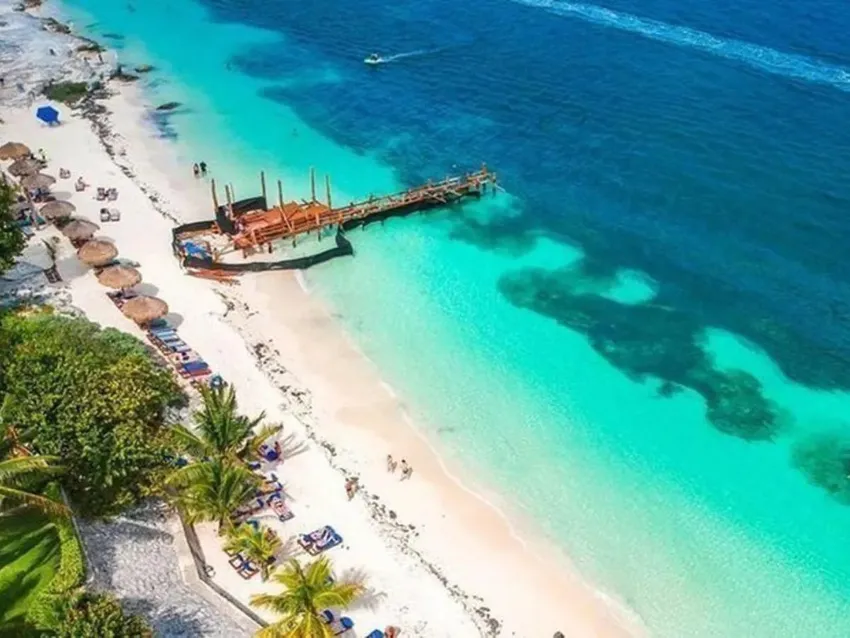 Aerial view of a Cancún beach with a pier, showing two distinct shades of blue water