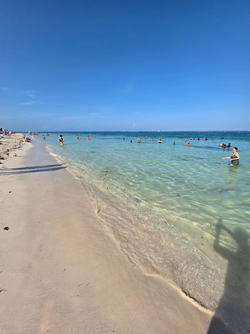 Puerto Morelos centro with clear turquoise water and swimmers along the shore in June