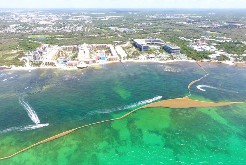 Aerial view of a private resort sargassum barrier enclosing the water in front of a Riviera Maya beachfront
