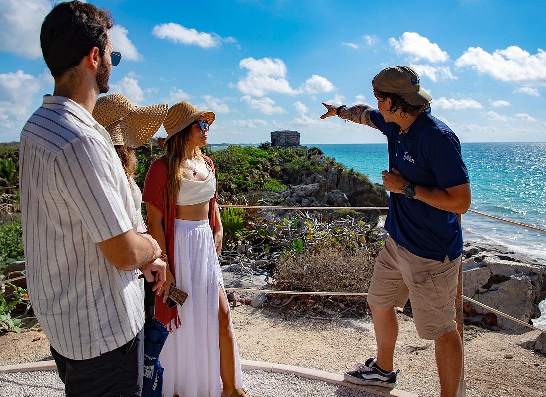 A guide explaining the site to visitors at the Tulum ruins